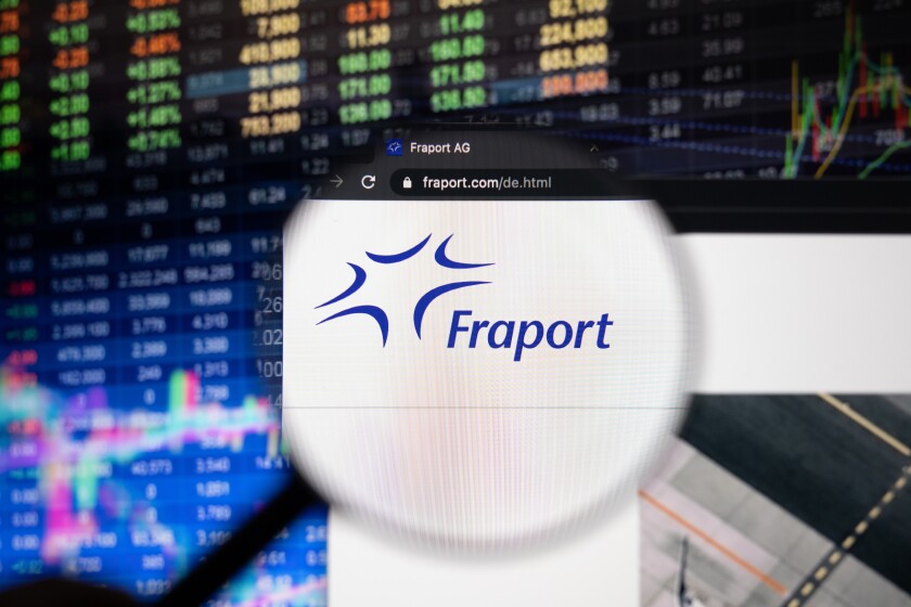 Fraport company logo on a website with blurry stock market developments in the background, seen on a computer screen through a magnifying glass