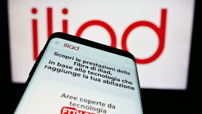 Mobile phone with website of telecommunications company Iliad Italia S.p.A. in front of business logo. Focus on top-left of phone display.