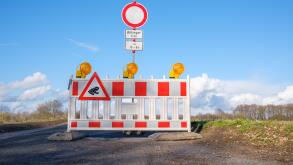 Roadblock with German traffic sign meaning "No through traffic, residents only between 18:00 to 8:00". Road closed with a barrier for toad migration.