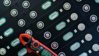 Electric vehicle lithium NMC battery with multimeter. Electric car battery manufacturing factory. Lithium-ion cell. Lithium NMC rechargeable battery.