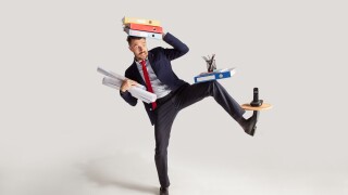 Young businessman in a suit juggling with office supplies in his office, isolated on white background