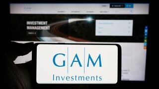 Person holding cellphone with logo of Swiss asset management company GAM Investments in front of business webpage. Focus on phone display.