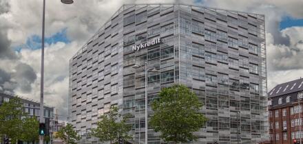 Copenhagen, Denmark - July 24, 2022: Modern gray, glass and steel Nykredit bank building at corner of Puggaardsgade and Kalvebod Brygge under blue clo
