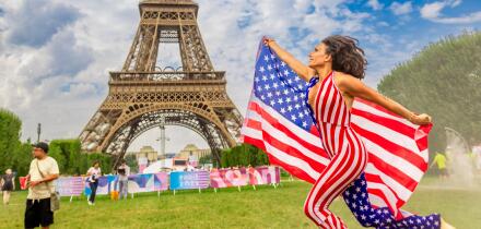 Patriotic American Woman jumping and cheering for Team USA and the Paris 2024 Olympics in front of the Eiffel Tower, Paris, France, Europe Copyright: