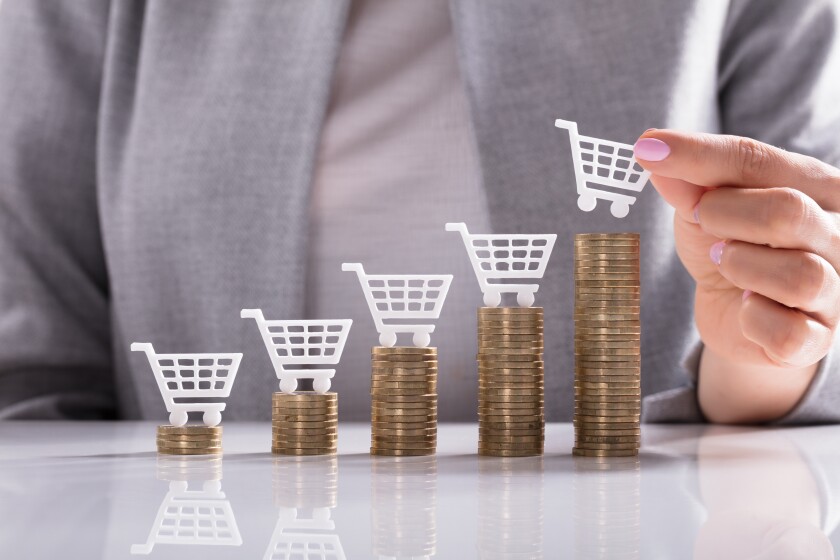 Businesswoman Placing Shopping Cart On Top Of Stacked Coins