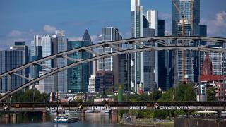 The river Main with the Deutschherrnbruecke bridge and a barge in front of the skyline of Frankfurt am Main, Hesse, Germany