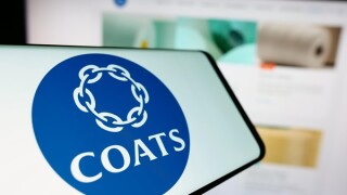 Mobile phone with logo of British textile material company Coats Group plc in front of business website. Focus on center of phone display.