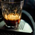 Close focus on double shot of hot espresso coffee on glass cup with dark scene of table.