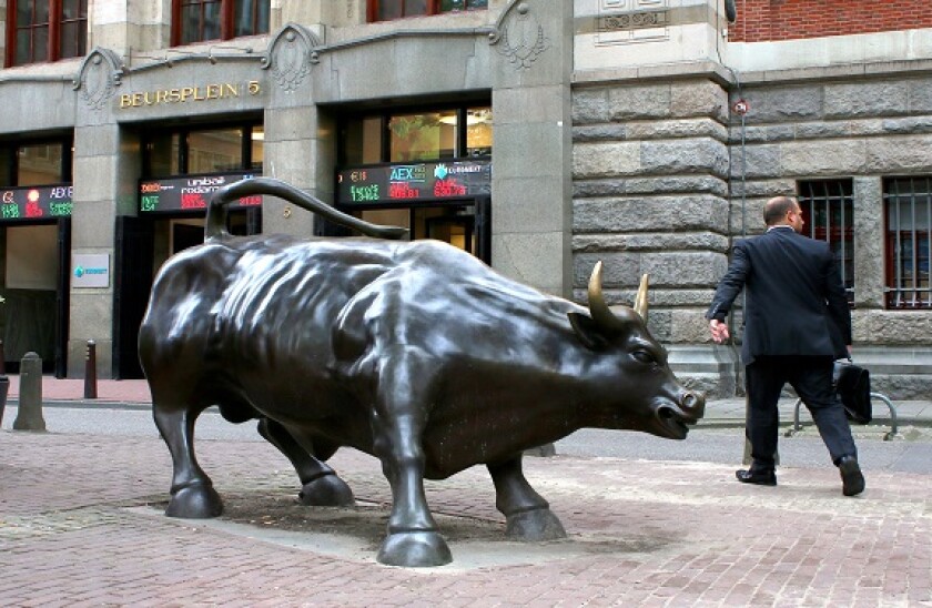 Statue of a charging bull in front of the Amsterdam stock Exchange at Beursplein in the Dutch capital, trader going to work