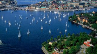 Aerial view of sailboats surrounding The Old Town of Stockholm during summer regatta on Saltsjon waters a bay of the Baltic Sea