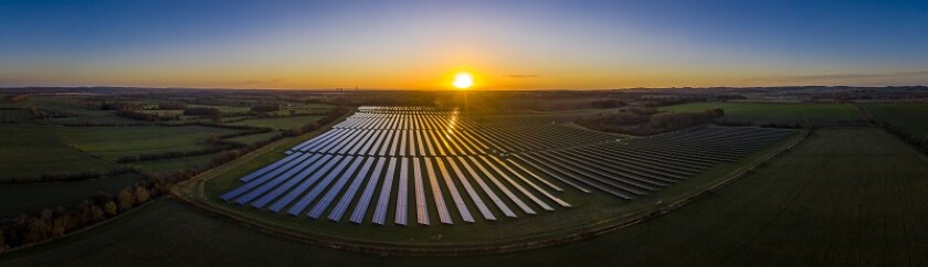 Aerial looking over a modern solar farm at sunrise in the English countryside panoramic