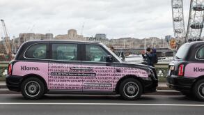 Black taxis with pink Klarna poster in Westminster London, UK