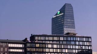 Glass building headquarters of the French bank BNP Paribas with the logo sign illuminated at sunset. Milan, Italy.
