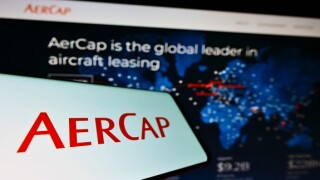 Cellphone with logo of aircraft leasing company AerCap Holdings NV on screen in front of business website. Focus on center-left of phone display.