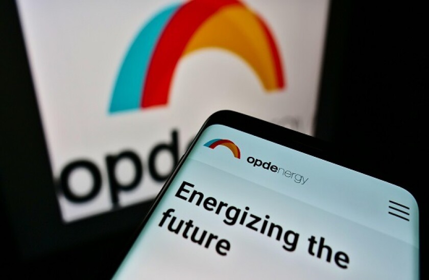 Smartphone with website and slogan of Spanish renewable energy company OPDenergy S.A. on screen in front of logo. Focus on top-left of phone display.