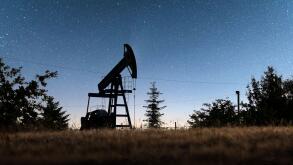 Pump jack silhouette on night sky with stars. Oil pump against incredible sky with Milky Way. Industrial concept
