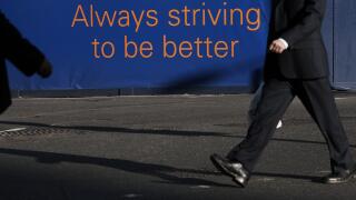 GREAT BRITAIN / England /Canary Wharf/ Banker in Canary Wharf with sign Always striving to be better.