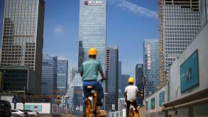 Men ride bicycles past construction sites near the headquarters of China Evergrande Group in Shenzhen, Guangdong province, China September 26, 2021. REUTERS/Aly Song