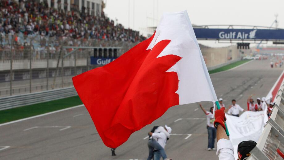 A marshal celebrates waving Bahrain flag after the Bahrain Formula One Grand Prix at the Formula One Bahrain International Circuit in Sakhir, Bahrain, Sunday, April 22, 2012. (AP Photo/Luca Bruno)
