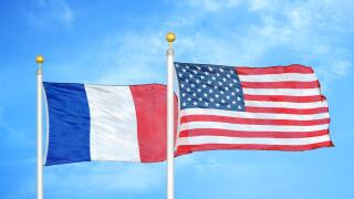 France and United States two flags on flagpoles and blue cloudy sky