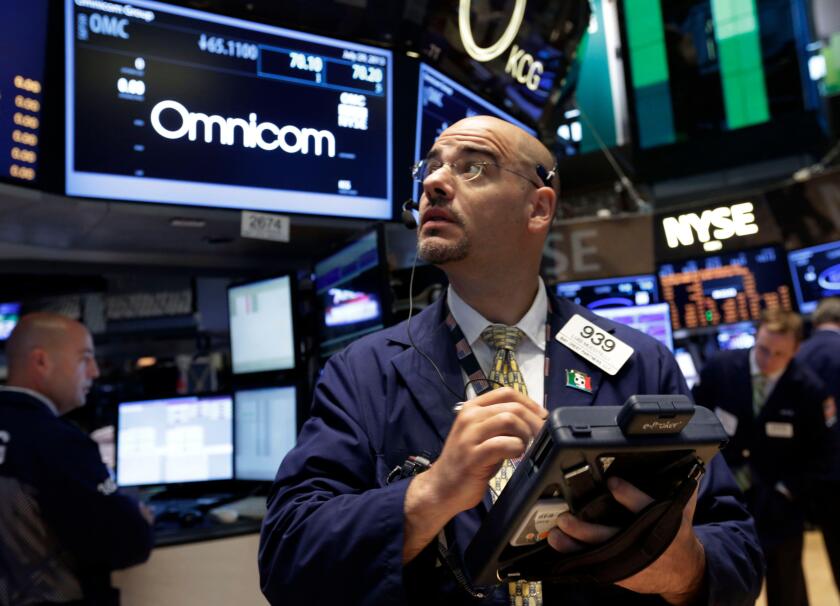 Trader Luigi Muccitelli works on the floor of the New York Stock Exchange Monday, July 29, 2013. Omnicom Group Inc. and Publicis Groupe SA say they are combining in a "merger of equals" that will create the world's largest advertising firm, one worth more