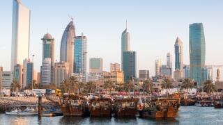 Traditional wooden dhows in fishing port with city skyline in the background. Kuwait