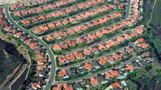An aerial view shows side-by-side homes with red-tile roofs that are crammed into this housing development among foothills in San Diego County in Southern California, USA. Such jam-packed suburban neighborhoods are common there because of the popularity o