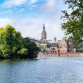 scenic view of a city waterfront with historic buildings and a lush green island in the middle of the water, the hague