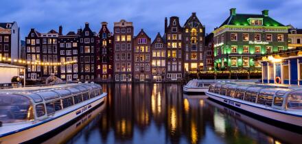 AMSTERDAM, THE NETHERLANDS - JANUARY 18, 2023: Cityscape of traditional Dutch houses during sunset at the Damrak canal in Amsterdam