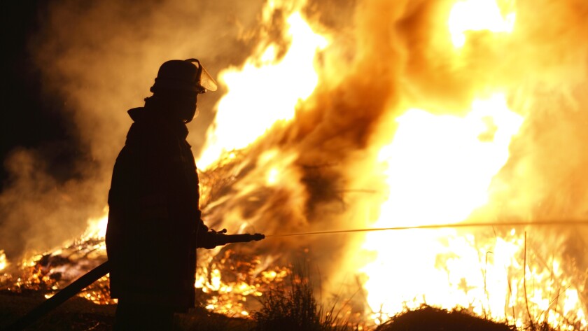 Firefighter Holding Hose Pointing Water Stream onto Fire