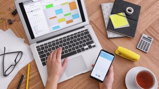 calendar on laptop and smartphone at wooden table-adobe-2022