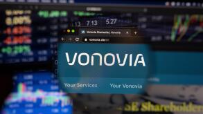 Vonovia company logo on a website with blurry stock market developments in the background, seen on a computer screen through a magnifying glass