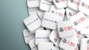 Logos of Credit Suisse and UBS Bank on a heap on a table. Concept for a possible merger or take over. Copy space. Web banner format.