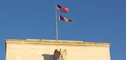 United States Federal Reserve headquarters in Washington DC, USA. Eccles Building with US National and Fed flags under clear sky in early morning.