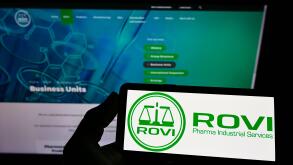 Person holding smartphone with logo of company Laboratorios Farmaceuticos Rovi S.A. on screen in front of website. Focus on phone display.