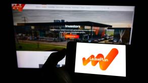 Person holding cellphone with logo of Dutch leasing company LeasePlan Corporation NV on screen in front of webpage. Focus on phone display.
