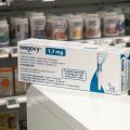 Packaging box of Wegovy (semaglutide) injectable prescription medication, weight-loss drug from Novo Nordisk AS. Pharmacy shop shelves in background.