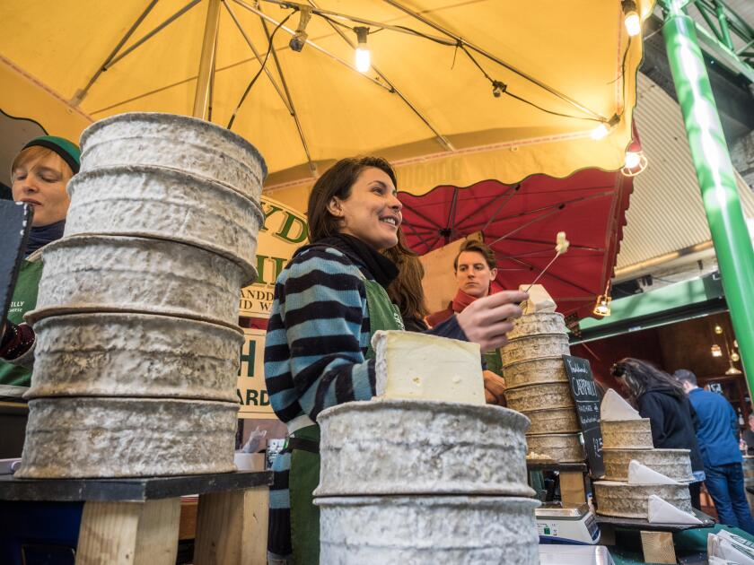 towers of cheese and cheese tasting at a cheese market stall in Borough Market, London