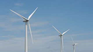 Three wind turbines, close-up of blades, against blue sky. Wind power "wind farm" turbines alternative energy, renwable energy.