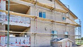 House with scaffolds under renovation with primer and base coat for new stucco application