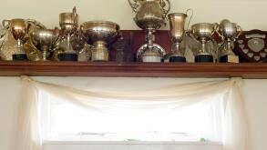 Trophies on a shelf above a list of honorary members plaque in the interior of the club house at the Mauchline lawn bowling green in Mauchline; Ayrshi