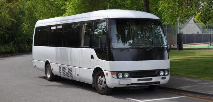 A small white tour coach, bus or mini-van used to transport passengers and tourists. Typically used for small group tours of around 21 passengers.
