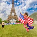 Patriotic American Woman jumping and cheering for Team USA and the Paris 2024 Olympics in front of the Eiffel Tower, Paris, France, Europe Copyright: