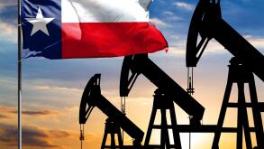 Oil rigs against the backdrop of the colorful sky and a flagpole with the flag State of Texas. The concept of oil production, minerals, development of