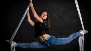 Aerialist woman doing some flexibility and strength tricks on silks