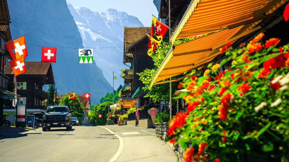 Picturesque cozy alpine village with shops and rustic wooden houses. Cute mountain village with flowery street and high mountains in background, Laute