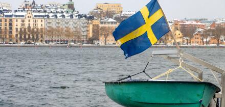 The Swedish flag flies above a ship moored on the shore in central Stockholm