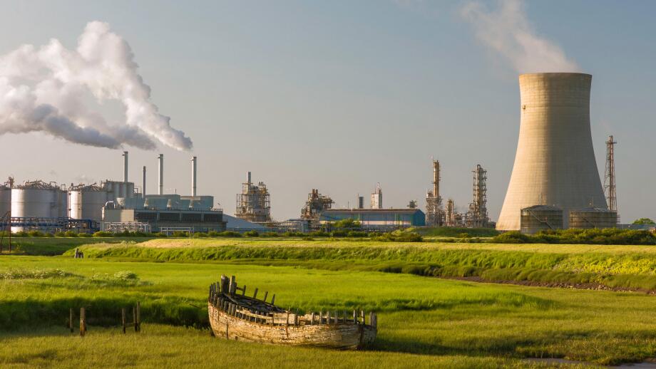 A chemical plant on the bank of the Humber estuary with derelict boat beached in the mud bank.