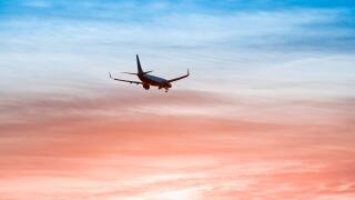 Large plane flies in the evening sunset sky, dramatic painted sky and airplane silhouette with clouds over Lisbon in Portugal
