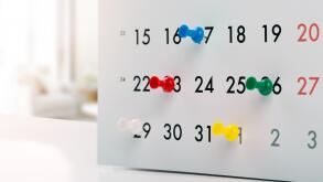 thumbtacks in calendar - concept of busy schedule